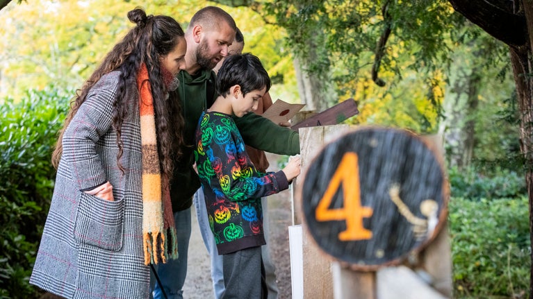 A family are solving clues and cracking codes, they are consulting their trail sheet next to station number 4.